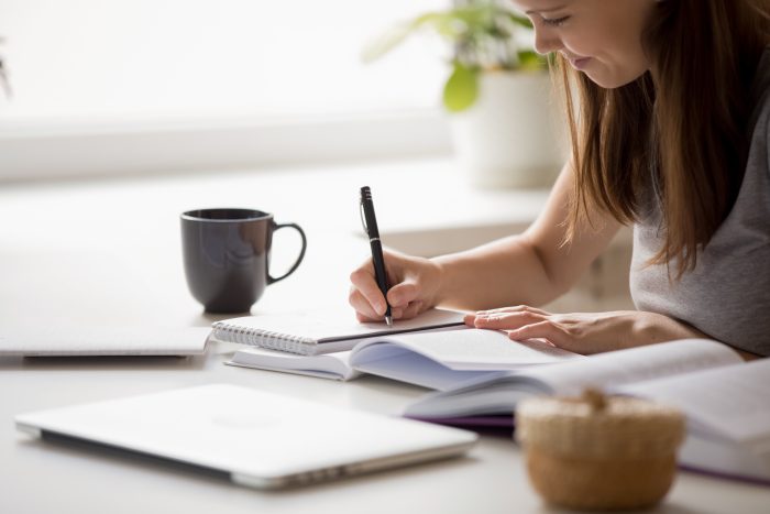 A young girl sat at a desk writing notes during a PMT online revision course.