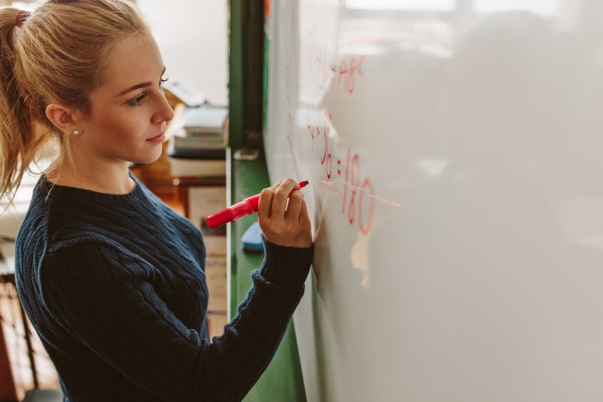 An A Level Further Maths student solving a maths problem on a whiteboard.