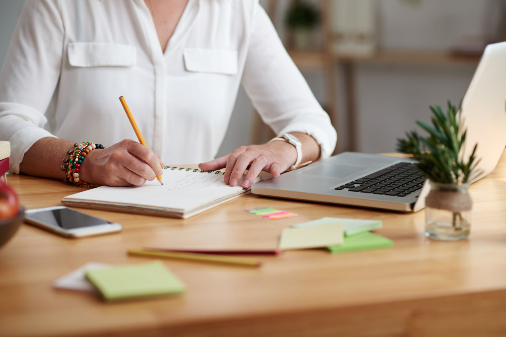 A female tutor sits at a desk, writing on a piece of paper to work out her tutoring rates.