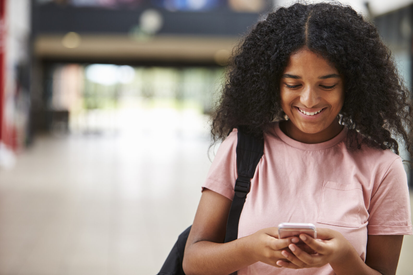 A teenage girls smile as she texts friends and family after collecting her exam results on GCSE Results day.