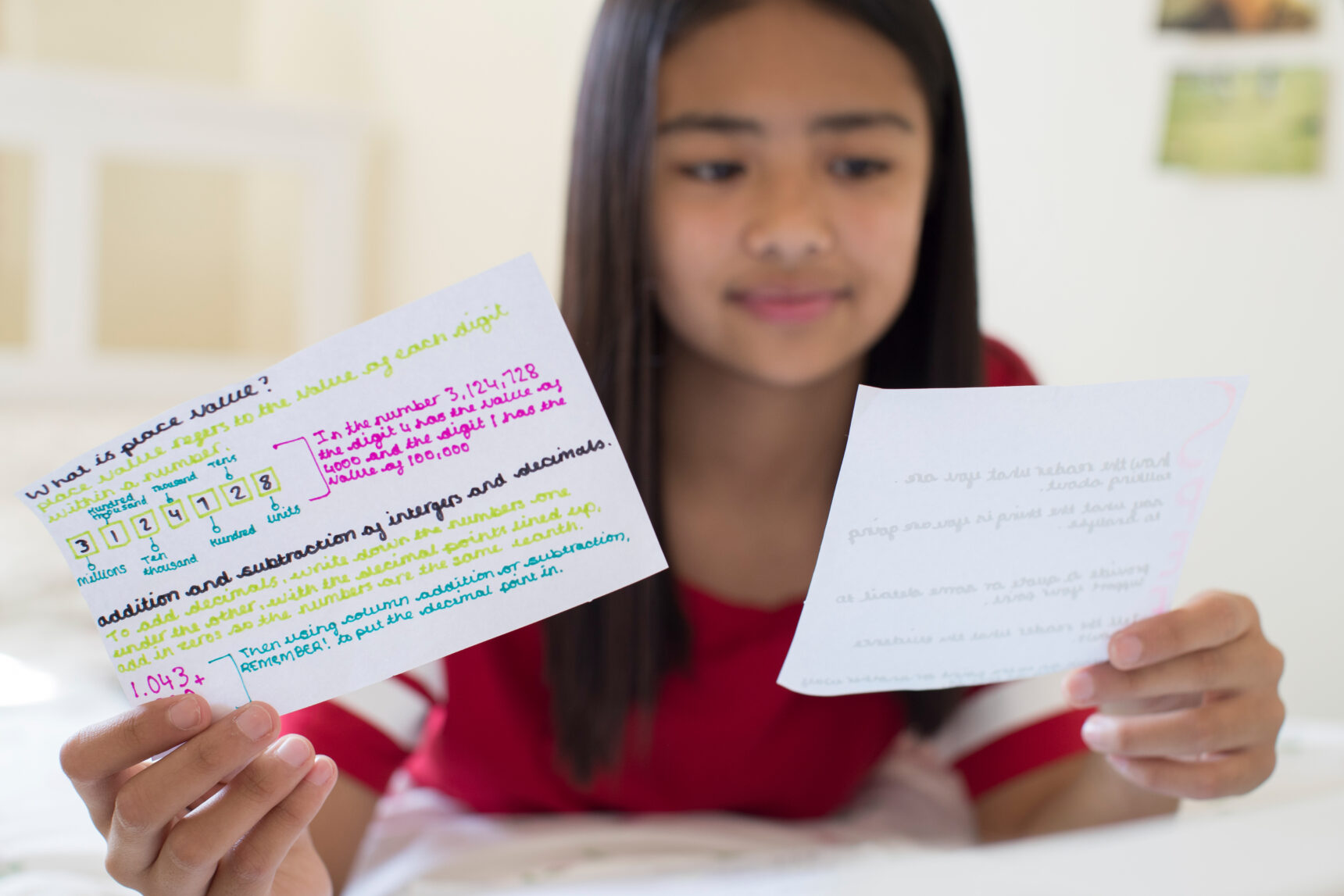 A female student is looking at handwritten flashcards as a way to revise effectively for her maths exam.