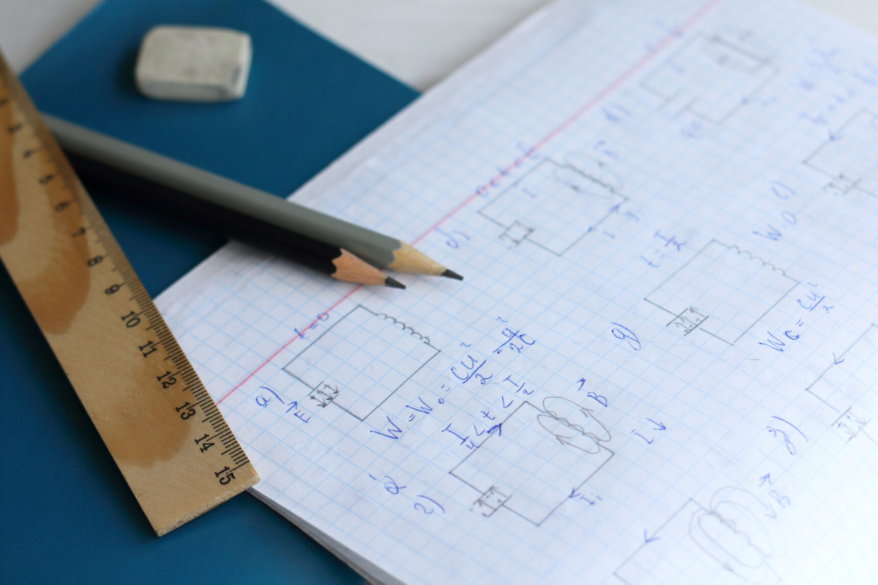 A student notebook showing physics formulae, pencils, ruler, and a rubber.