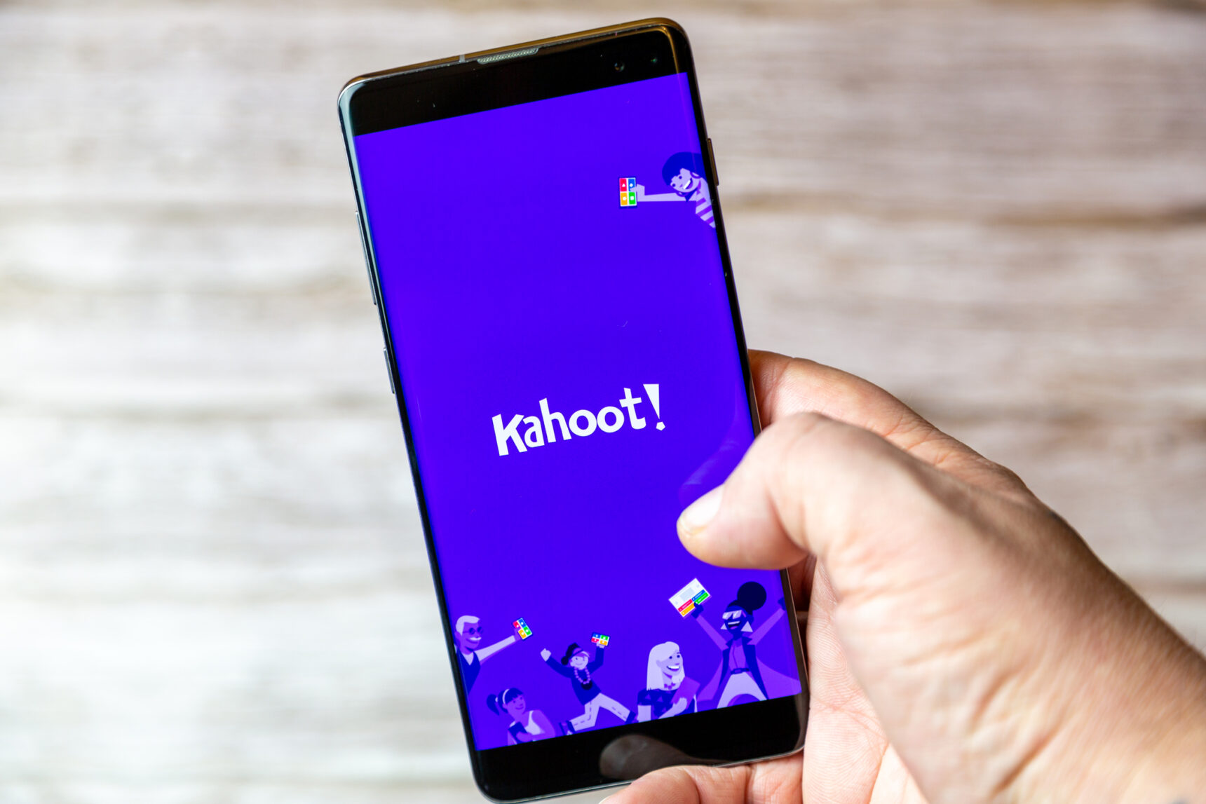 A hand holding a mobile phone showing the Kahoot app on the screen, one of the best teacher apps for gamification.