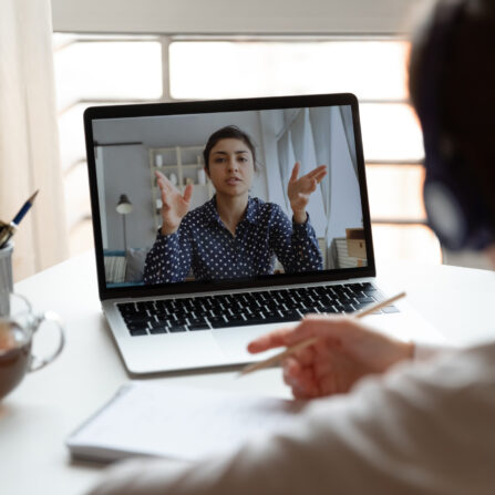 A student wearing headphones is listening to a tutor during an online GCSE tutoring session.