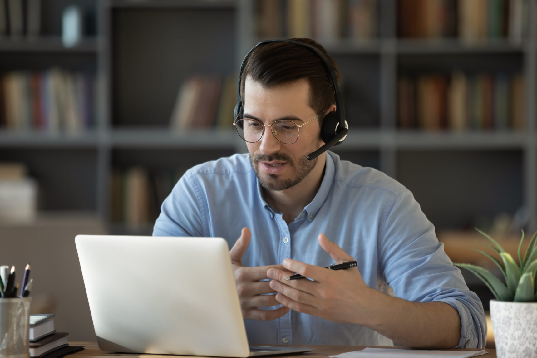 A male online maths tutor wearing a headset talks through a worked example as part of an online tutoring session.