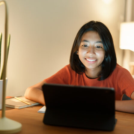 A female student is smiling as she takes part in an online mock exam preparation course.