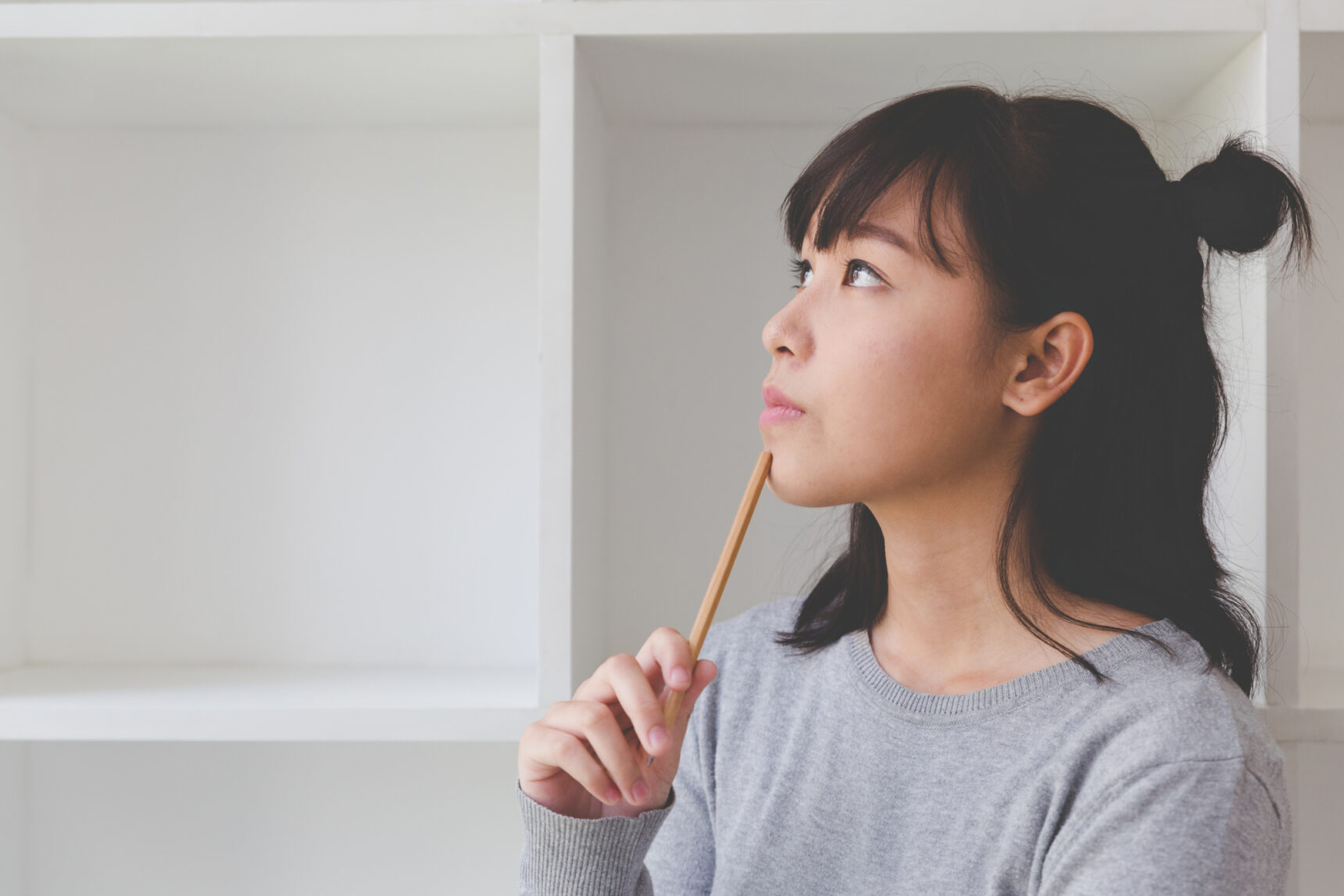 A student holding a pencil in a thoughtful pose as she thinks about what to write for the UCAS personal statement 2026.