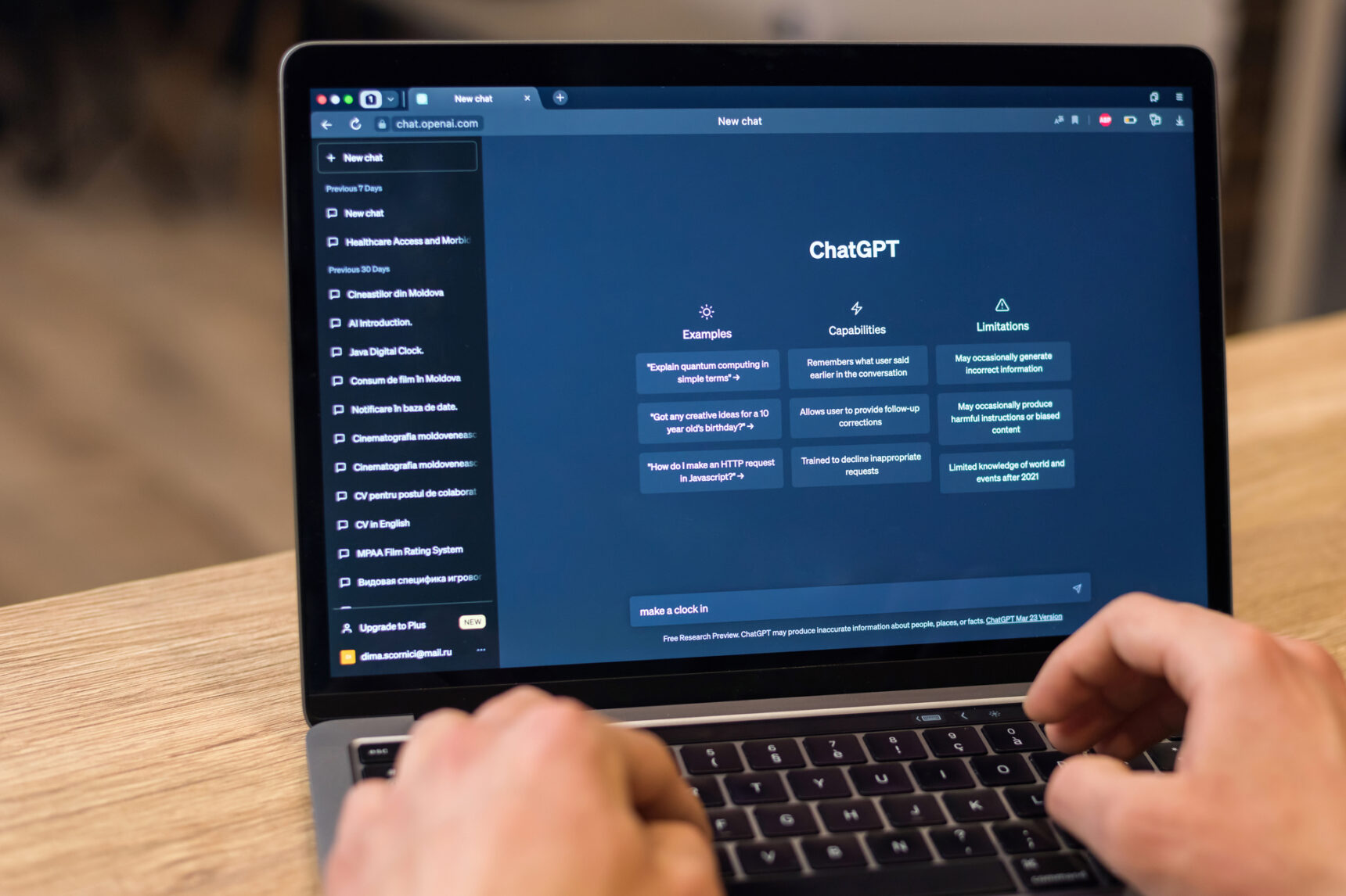 A student is typing on a laptop keyboard with the screen showing the ChatGPT home page.