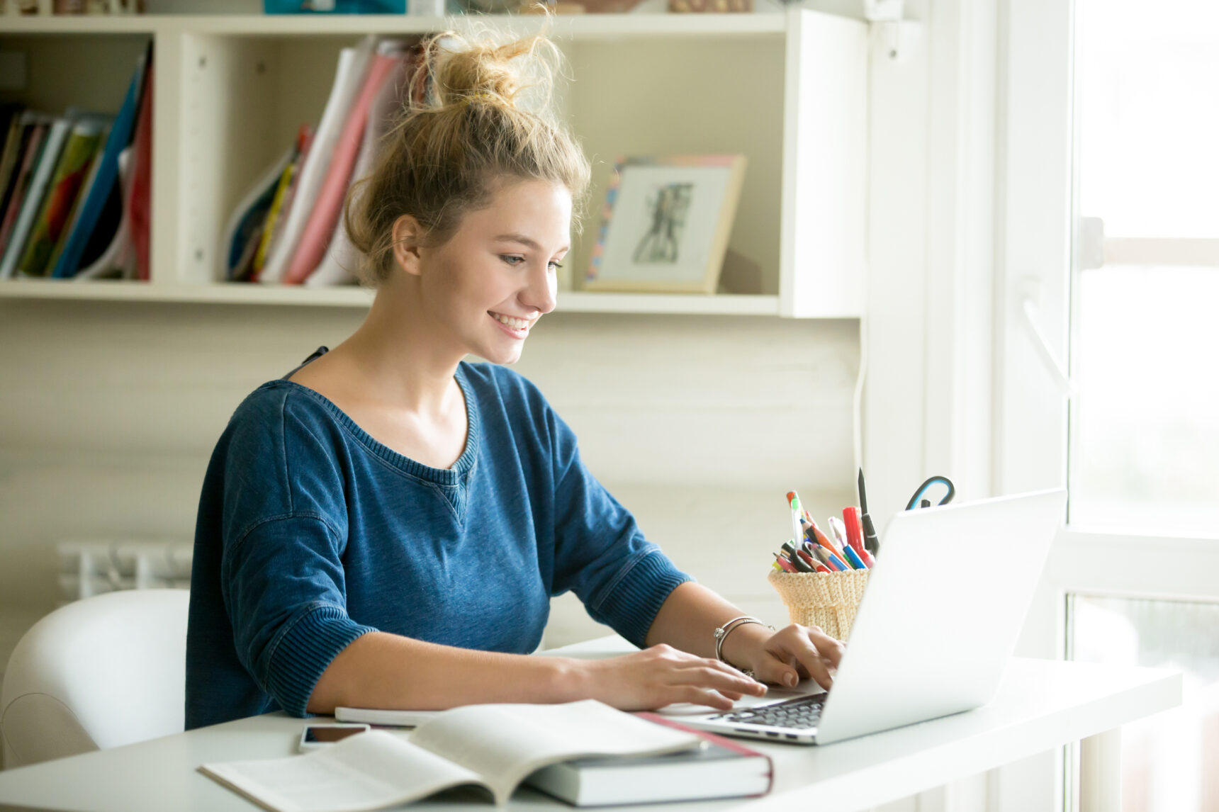 A female online tutor is smiling as she delivers a maths lesson to a student.