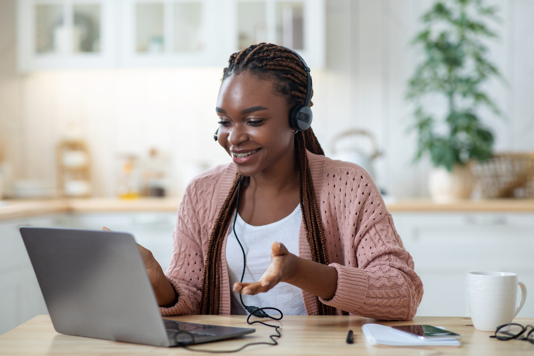 A female tutor is smiling as she delivers a lesson via an online tutoring platform.