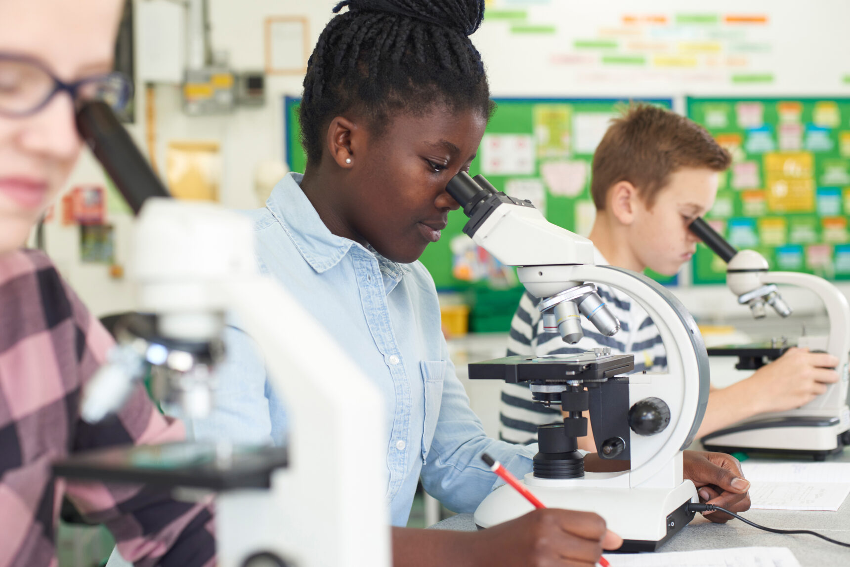 Students looking through microscopes in a GCSE Science lesson.