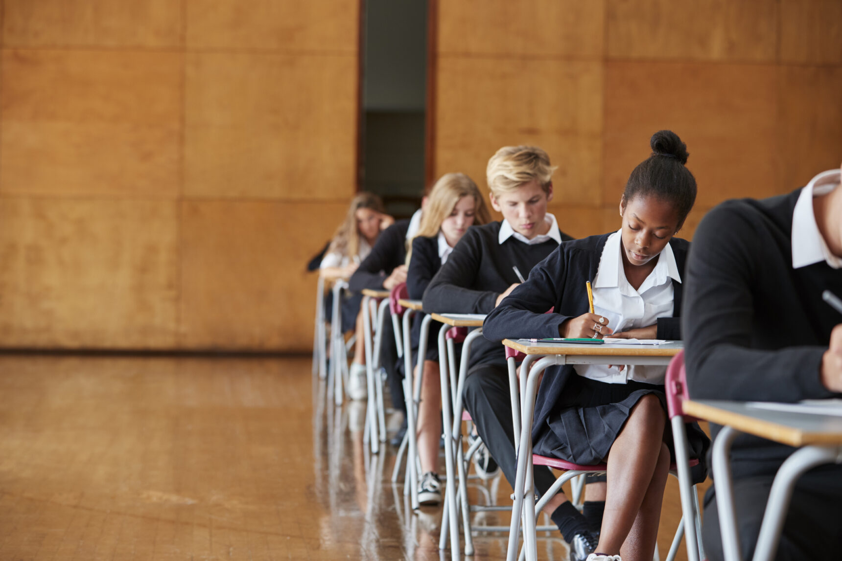 Students are sitting their GCSE English Language exam in an exam hall.