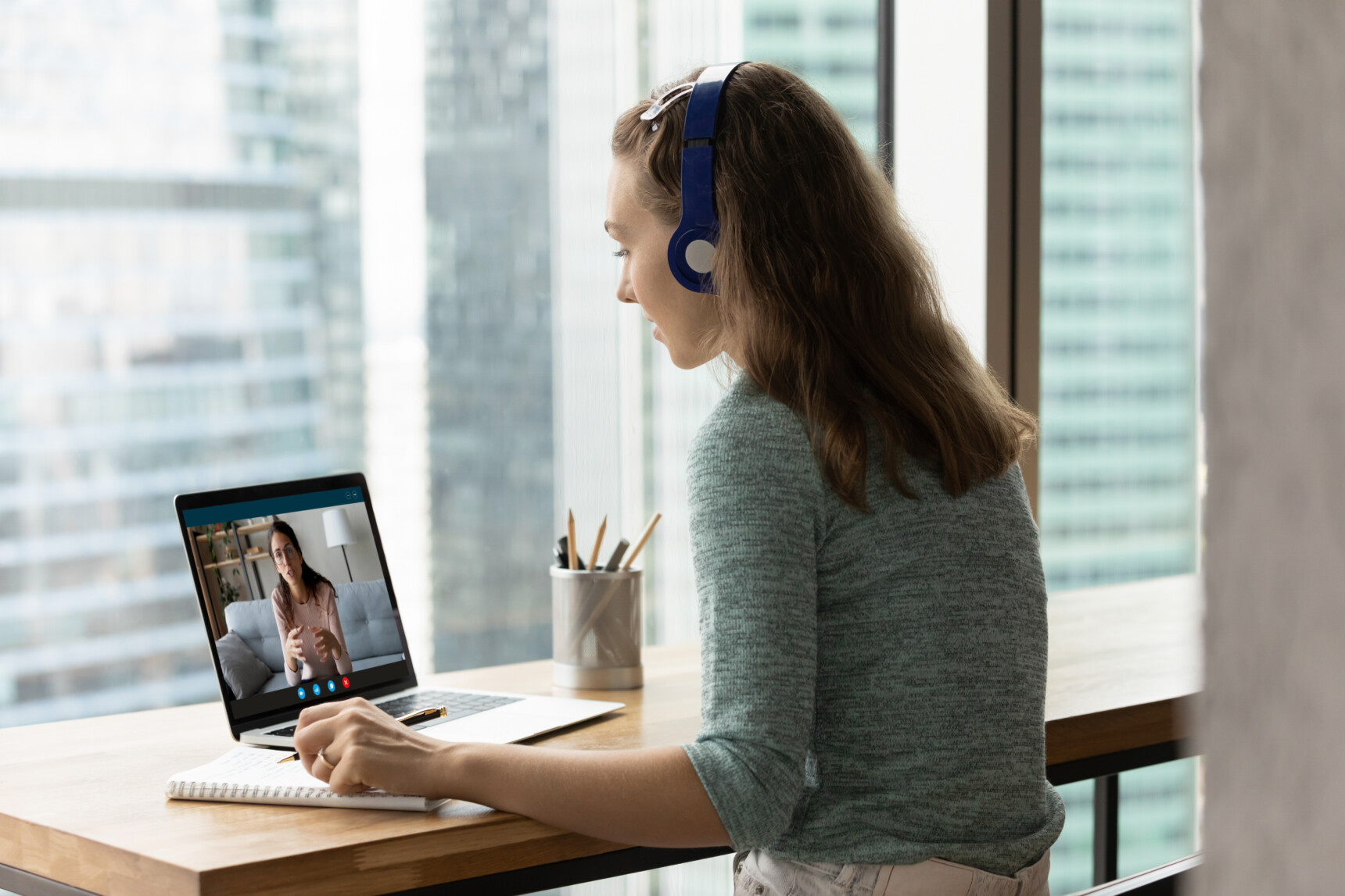 A teenage girl wearing a headset is using a laptop for online tuition.