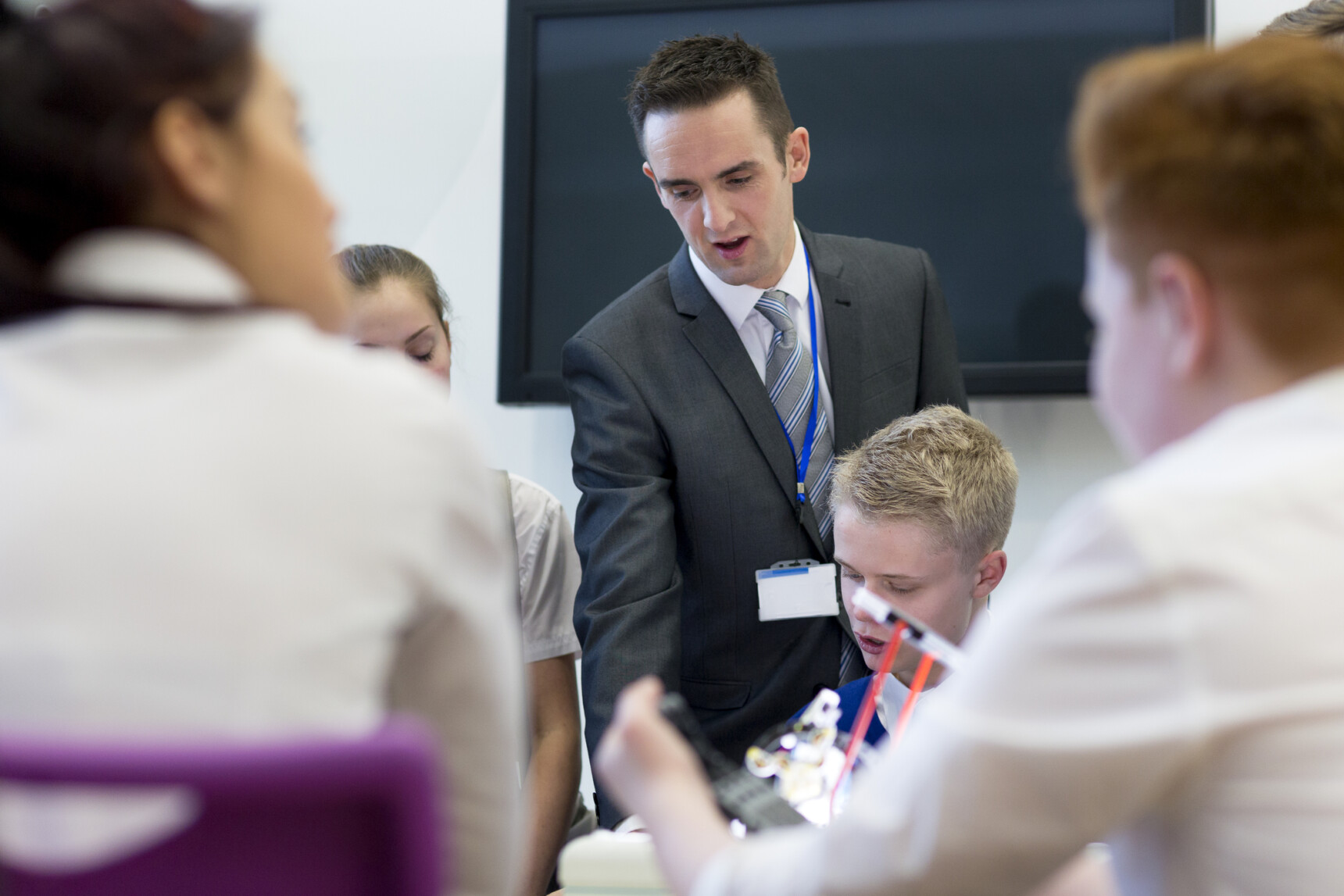 Teacher supporting students in a physics lesson about Newton's third law.