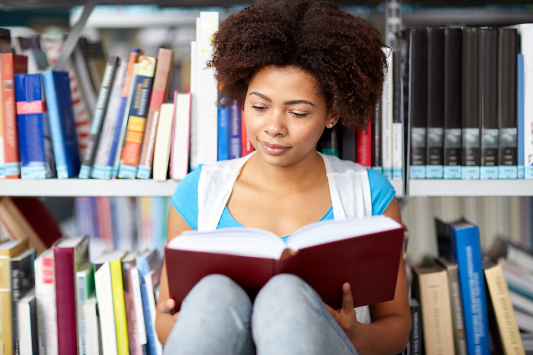 Female student reading a book in the library as part of a wider reading supercurricular activity.